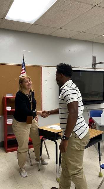 Male student shaking female teacher's hand.